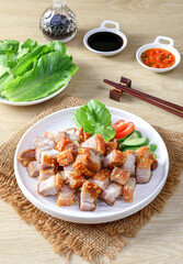 Crispy pork belly on white plate and dipping sauce on the wooden table