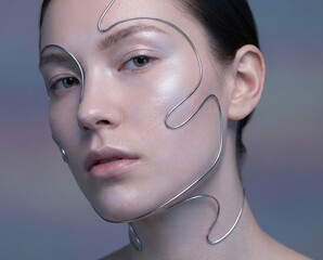 Conceptual futuristic beauty portrait of a woman with perfect skin and thin metallic, sinuous silver wires tracing the contours of her face and neck