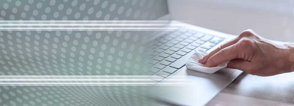 Woman disinfecting laptop keyboard; prevention of virus and bacteria infection; panoramic banner