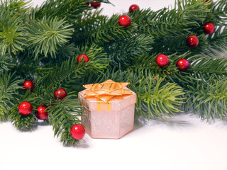 Pink Gift Box with Golden Ribbon in Christmas Pine Arrangement with Red Berries