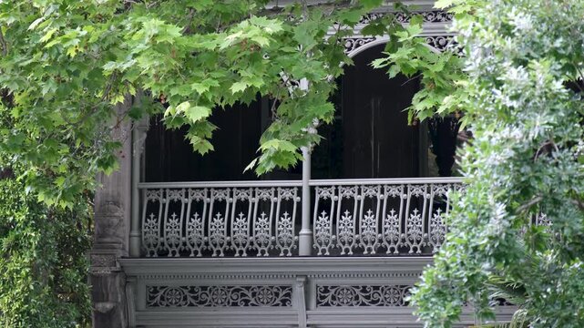 A close-up view of an ornate Victorian-era balcony in Melbourne, Australia, featuring decorative cast-iron lacework. Classic terrace architecture, heritage design, in a leafy historic neighbourhood.