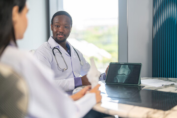 Diverse medical team african male doctor and female doctor collaborating and reviewing medical documents writing and discussing patient data in hospital office, teamwork in healthcare, patient care