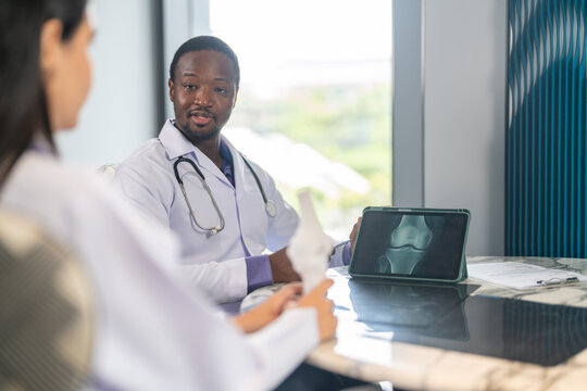 Diverse medical team african male doctor and female doctor collaborating and reviewing medical documents writing and discussing patient data in hospital office, teamwork in healthcare, patient care - Powered by Adobe