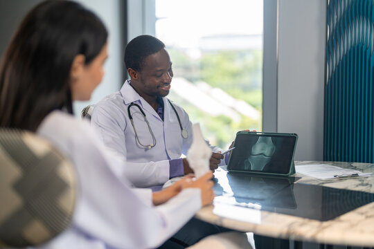 Diverse medical team african male doctor and female doctor collaborating and reviewing medical documents writing and discussing patient data in hospital office, teamwork in healthcare, patient care