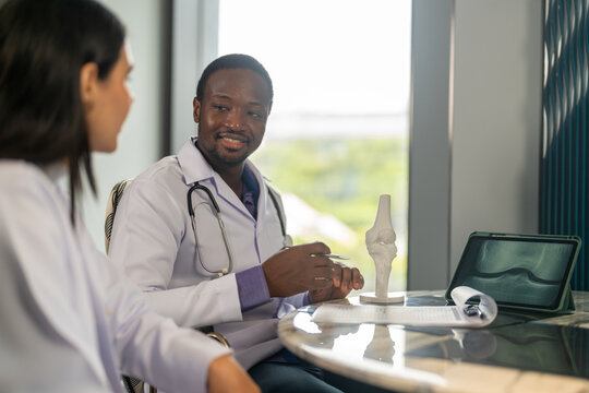Diverse medical team african male doctor and female doctor collaborating and reviewing medical documents writing and discussing patient data in hospital office, teamwork in healthcare, patient care