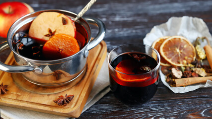 Homemade mulled wine in a ladle, spices, oranges and apples