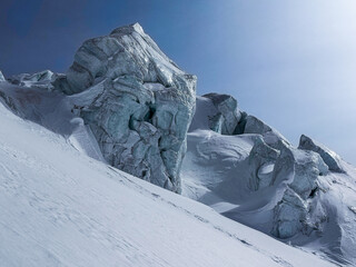 Dramatic ice formations and rugged glacier textures on a steep alpine slope under clear winter skies.A striking natural landscape showcasing shapes carved by snow, wind, and cold.