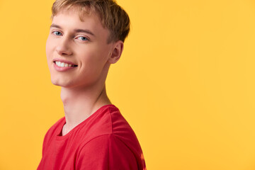 Smiling young adult in a red shirt against a vibrant yellow backdrop, casual studio shot conveying friendly energy, approachable vibe and everyday lifestyle appeal
