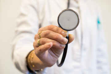 Close-up of Doctor's Hand Extending Stethoscope with Rings and Bracelets, Unsafe Medical Environment.