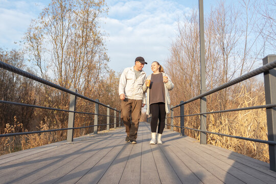 Casual middle-aged woman enjoys a coffee break while walking in park. - Powered by Adobe