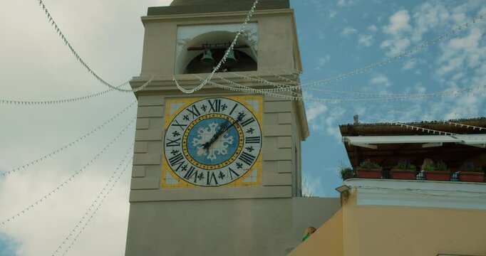 Historic clock tower Torre dell Orologio and holiday lights above the Piazzetta in Capri on summer day