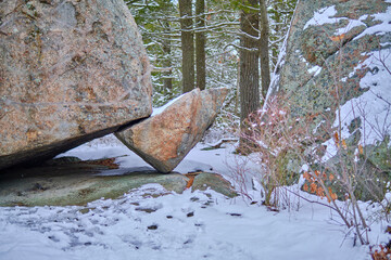 Large boulder balancing on a small rock covered in snow. © Ivan