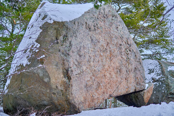Large boulder balancing on a small rock covered in snow. © Ivan