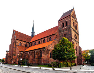 A brick church is pictured against a black background, with a steeple and an orange roof