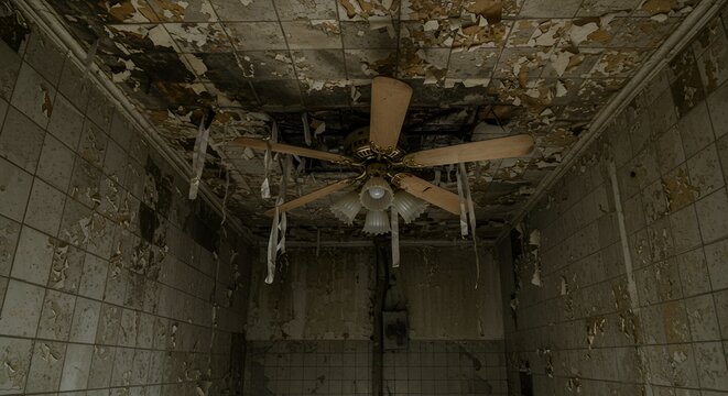 A peeling and damaged abandoned room features a desolate, non-functional ceiling fan fixture.