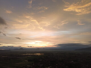 Fototapeta premium Epic sunset with orange and pink clouds above a vast landscape, blending warm tones with dramatic shadows for a striking atmospheric scene.