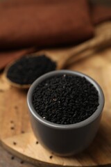 Aromatic black caraway in bowl and spoon on table, closeup