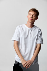 Obraz premium Young man wearing a white t shirt in a simple studio setting, casual and relaxed pose, clean style, emphasis on everyday fashion and comfortable attire