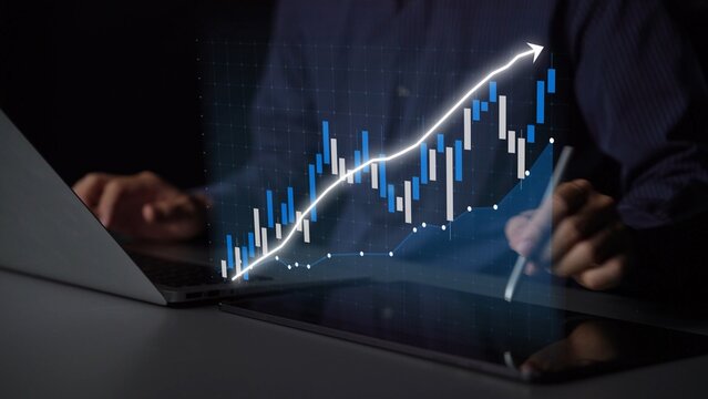 A focused businessman analyzes financial data trends on a laptop, showcasing a growth graph in a contemporary workspace, emphasizing technology and analysis. Copula