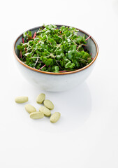 Organic Broccoli Sprouts on White Background Next to Sulforaphane Supplement