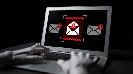 A robotic hand reaches for a laptop screen displaying a warning about fraudulent emails, highlighting the importance of cybersecurity in the digital age. Gantry