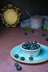 A rustic wooden bowl overflows with ripe blueberries that roll in different directions, showcasing their natural variations in size and shape.