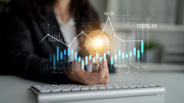 A business professional holds a glowing light bulb symbolizing innovative ideas amid financial charts and graphs, representing technology and market growth in modern business. Scalp
