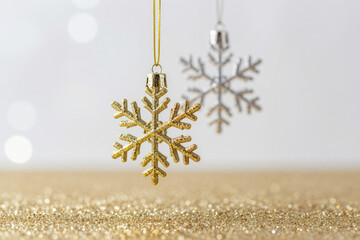 Elegant gold and silver snowflake ornaments gracefully shimmer on a sparkling glitter base, capturing the enchanting festive spirit of winter holidays and celebrations