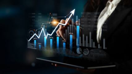 A professional businesswoman in a suit engages in financial analysis using a tablet, showcasing digital graphs that represent growth and trends in a corporate setting. Scalp