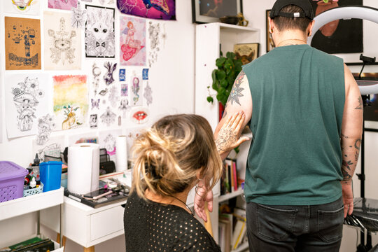 Tattoo artist consulting client about new tattoo design