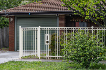 A metal front fence with decorative vertical bars and a secure gate stands at the boundary of a...