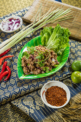 Thai larb salad with minced meat, herbs, onions, and spices, served with lettuce and chili.