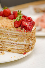 A homemade delicious layered honey cake, decorated with berries on top, close-up. It's so tasty! Let's try it!