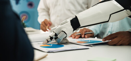 A robotic arm collaborates with business professionals during a meeting, focusing on data analysis...