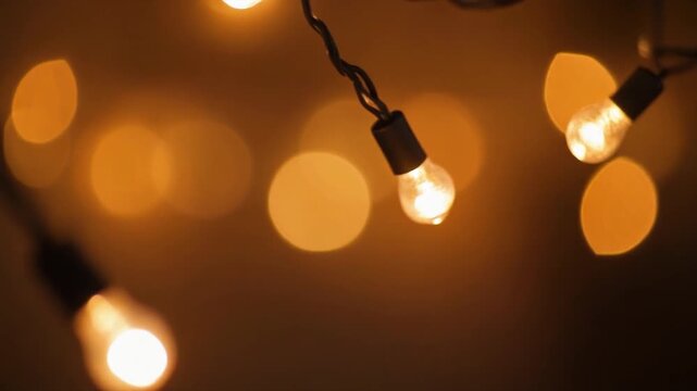 Close-up of warm glowing string lights creating a cozy bokeh effect in a dark setting.