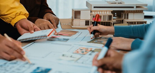 A group of architects and designers collaborates on an architectural project, sketching plans and discussing innovative ideas at a design studio workspace. SACTR