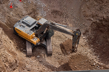  Excavator digging on a construction site, moving soil and rocks during groundwork and foundation preparation.