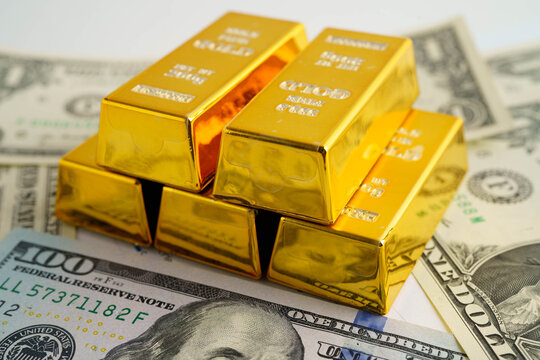 Gold bars on US dollar banknote money, finance trading investment business currency concept.