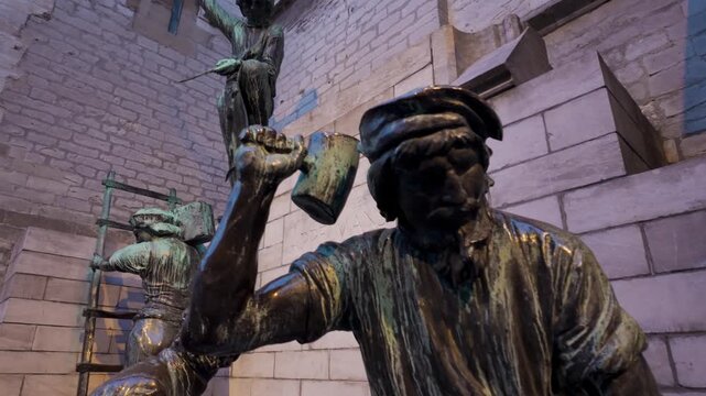 Pieter Appelmans monument in Antwerp. Bronze statues of medieval stonemasons and architects with stone wall in background near the Cathedral of Our Lady