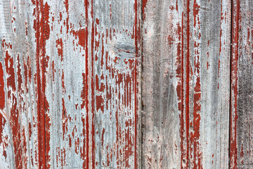 Obraz premium Close-up of weathered wooden planks with red and gray peeling paint, textured surface ideal for rustic backgrounds.