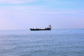 Traditional Southeast Asian Fishing Boat Sailing Across the Wide Ocean Horizon at Sunrise.