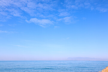 Obraz premium Clear Blue Sky and Ocean Horizon Background with Distant Mountains and Copy Space