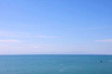 Fototapeta premium Vast Open Sea and Clear Blue Sky Horizon with Distant Island and Small Boat