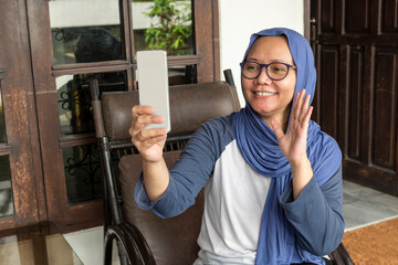 Indonesian hijab woman is waving to the camera and having video call.