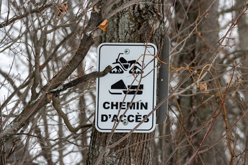 Canada, Quebec, 23 November 2025 : Snowmobile trail access sign on forest tree during wintertime season