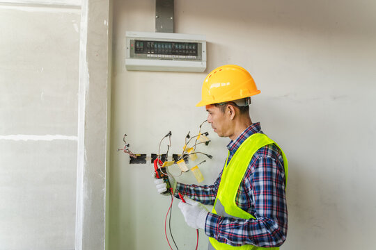 Professional electrician working on electrical wiring installation with safety equipment in modern construction site interior - Powered by Adobe