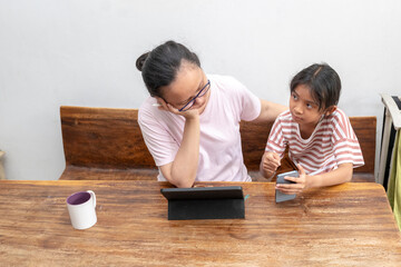 Indonesian woman and daughter are working a project together at home