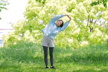屋外で準備運動をする40代女性