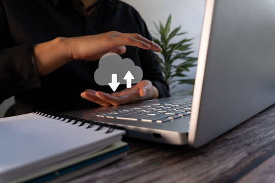 A businesswoman in front of a computer, protecting a virtual cloud icon with upload and download arrows