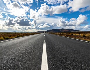 Long road, white line to mountains under a cloudy sky